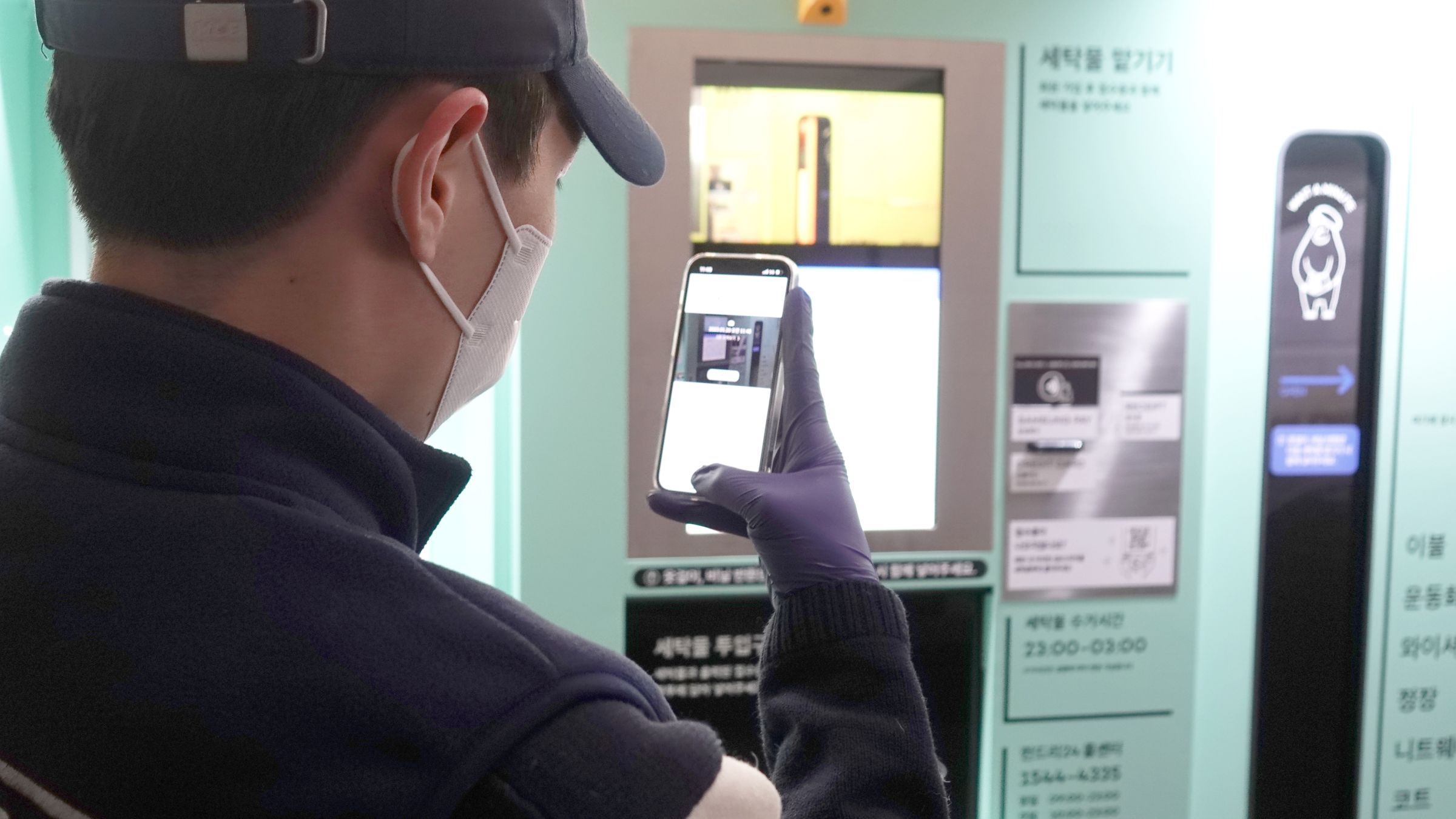 크루가 무인 세탁함 화면을 휴대폰으로 촬영하는 모습